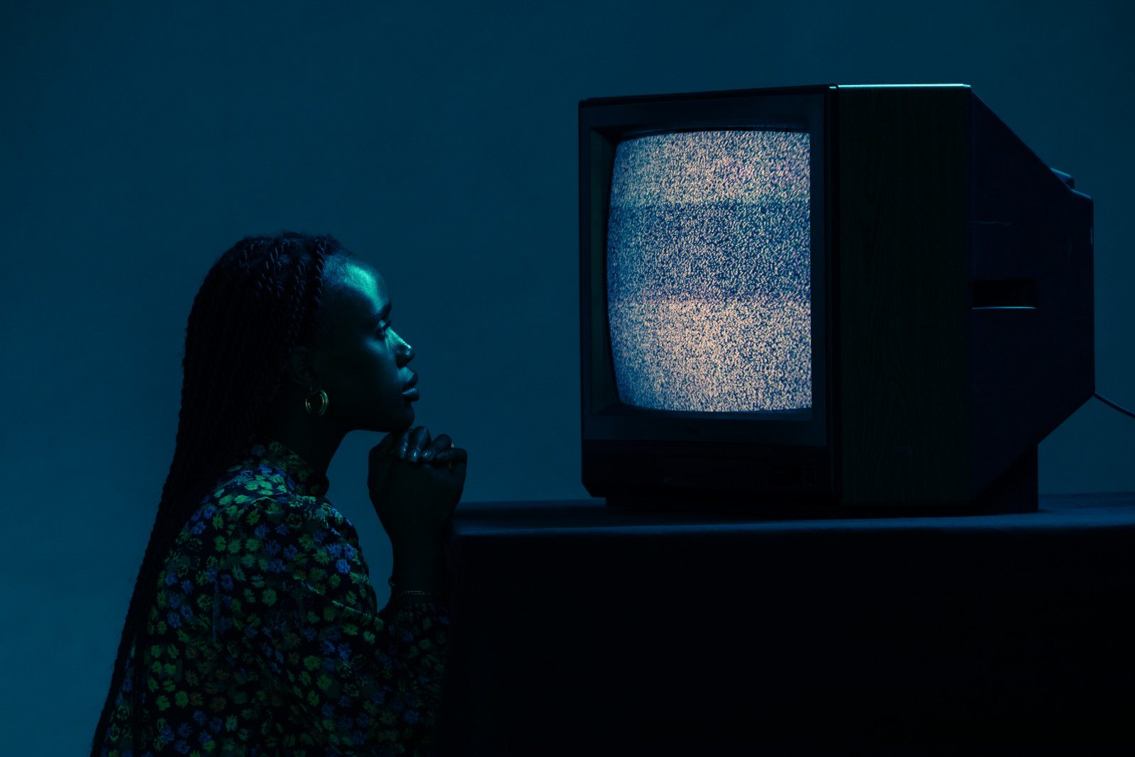 A woman in profile watching a television full of static